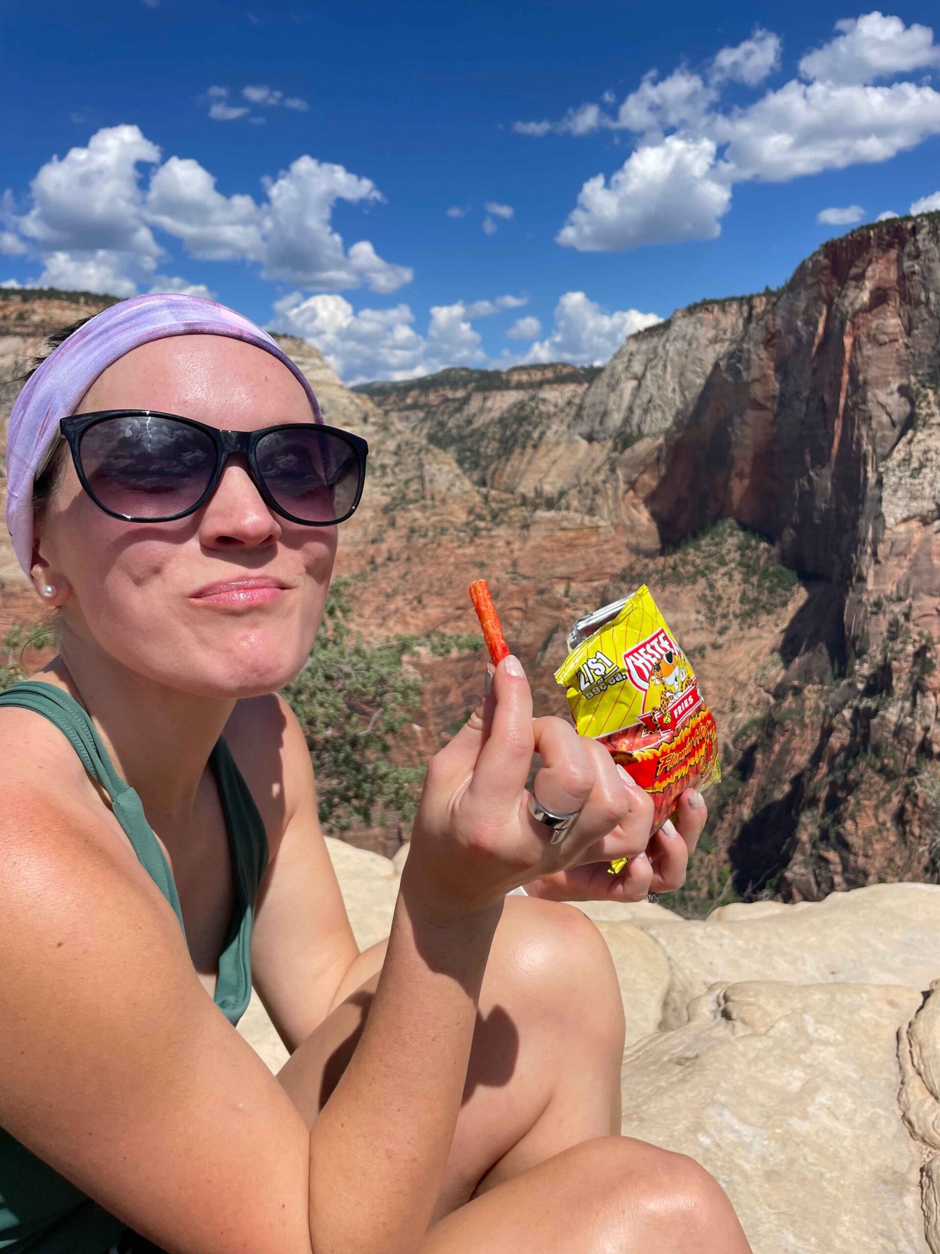 Girl hiker eating Cheetos at the top of Angels Landing