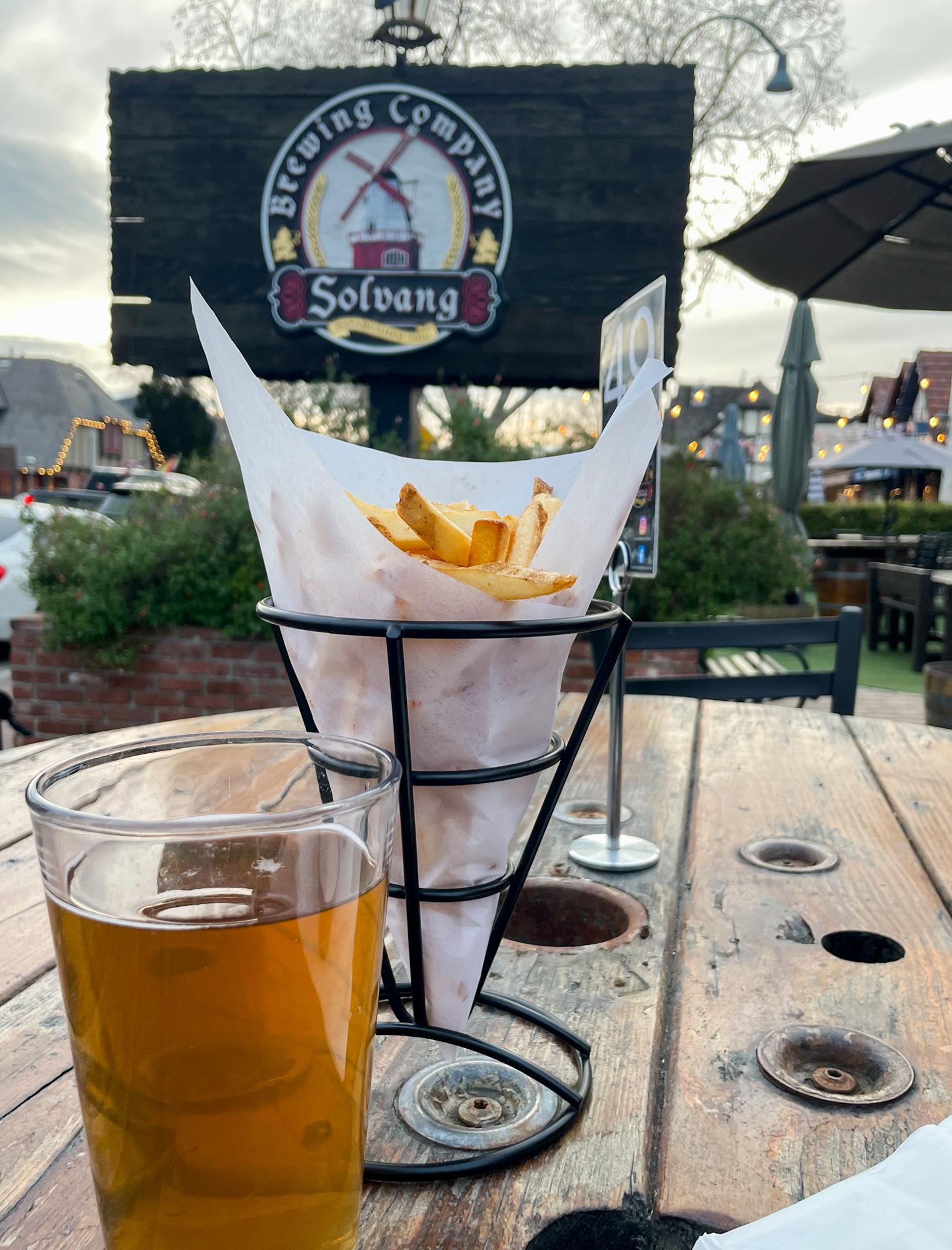 Beer and fries on a table with the Solvang Brewing Company sign in the background 