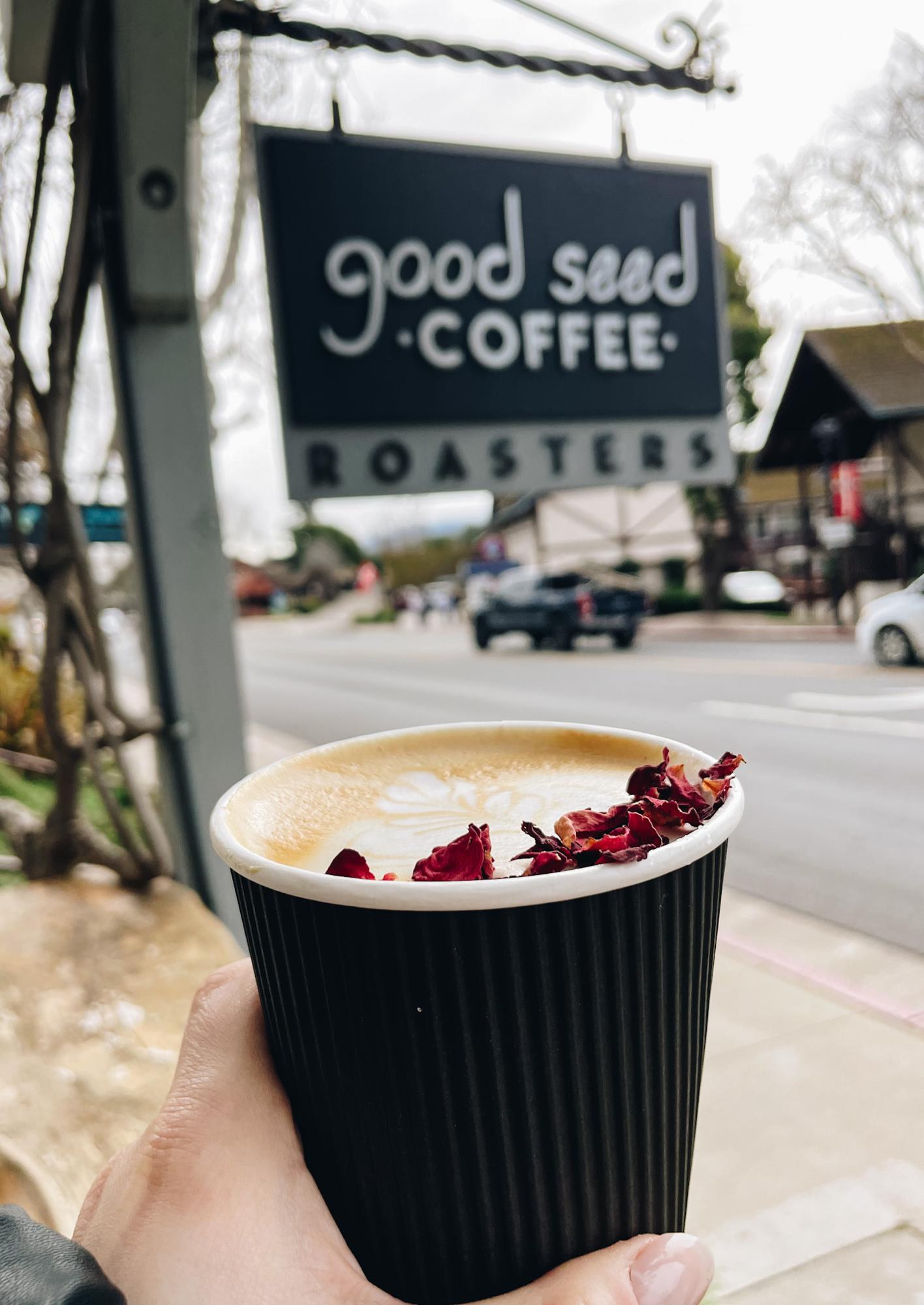 Good Seed Coffee Roasters exterior with rose latte in hand