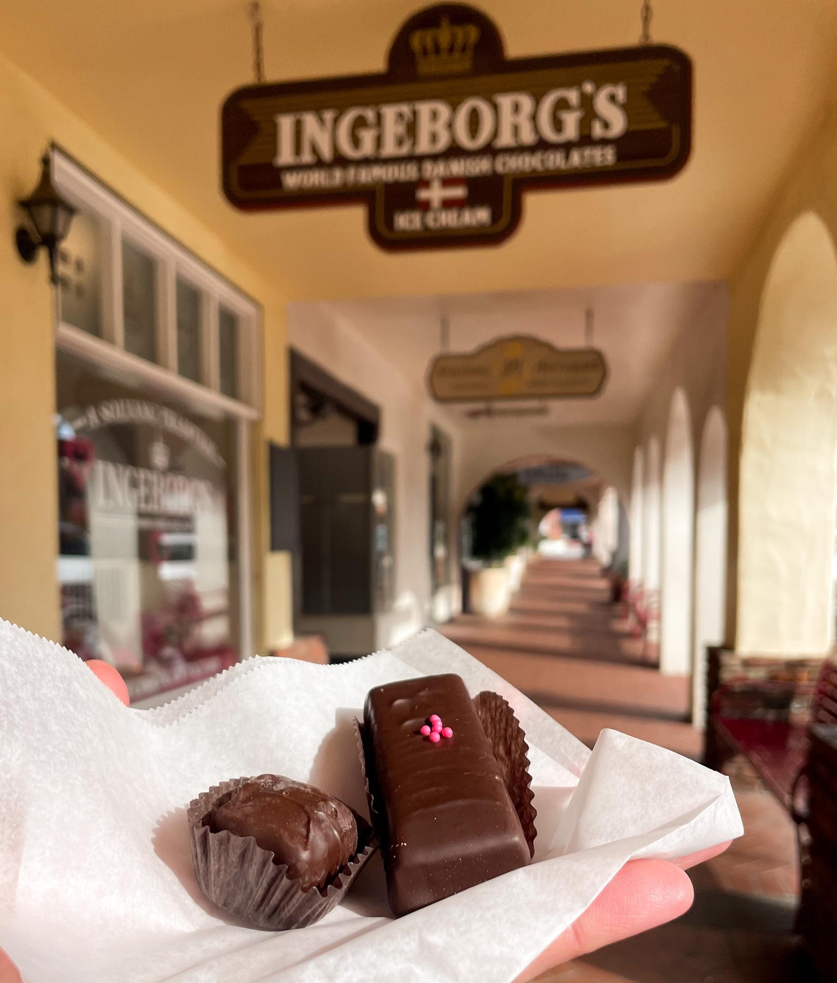 Two chocolates in hand with the Ingeborg's Chocolate sign in the background